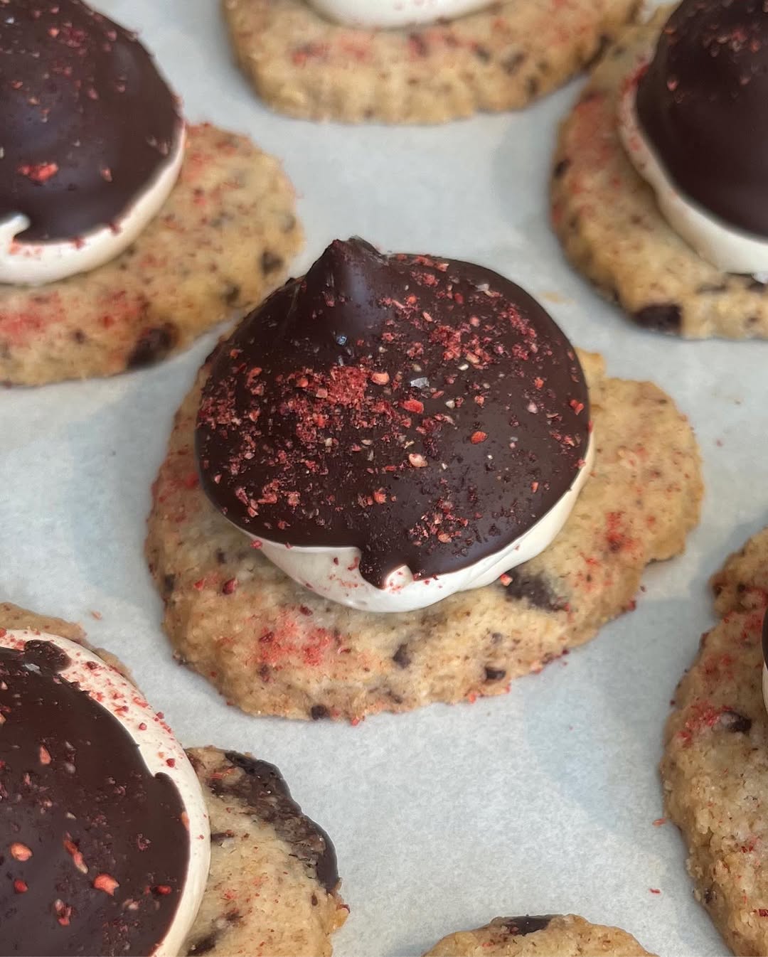 Chocolate ganache cookies with freeze-dried raspberry on parchment