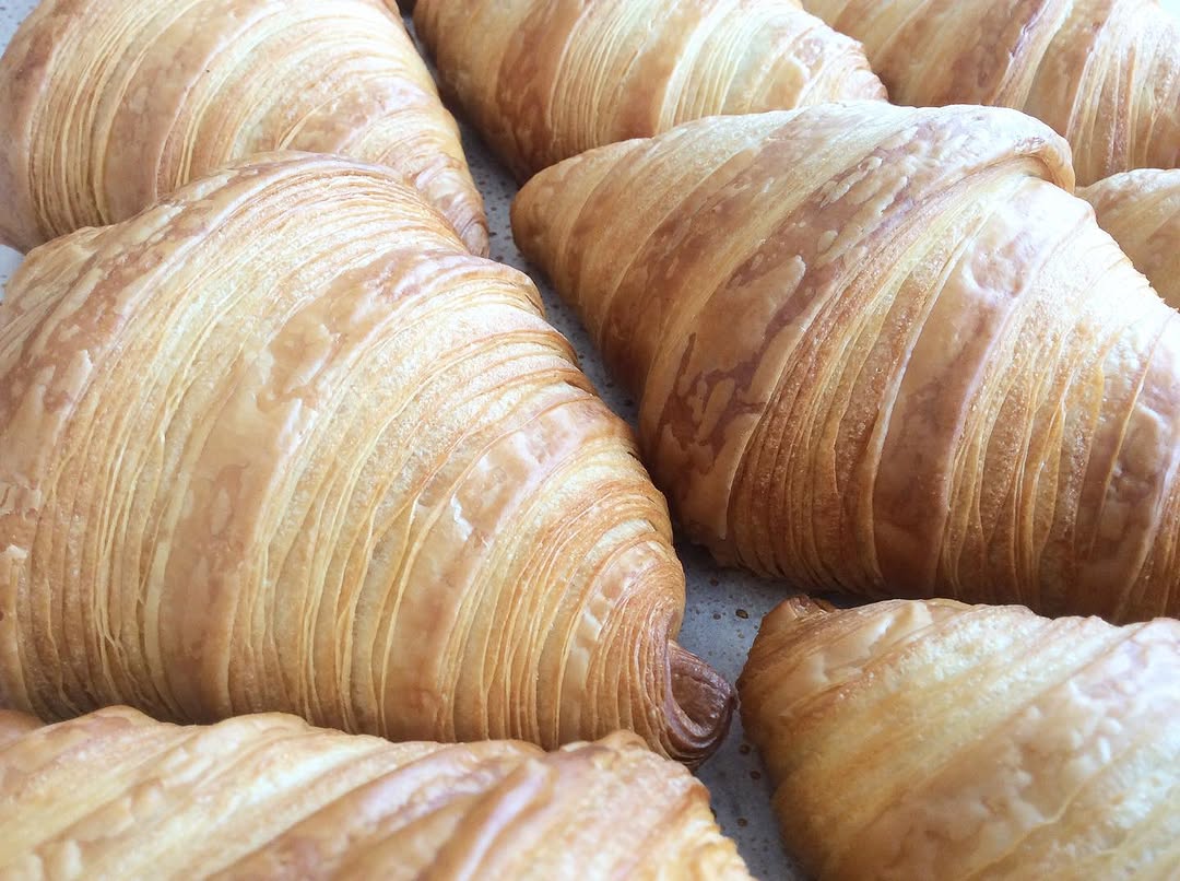 Golden butter croissants fresh from the oven, laminated layers visible